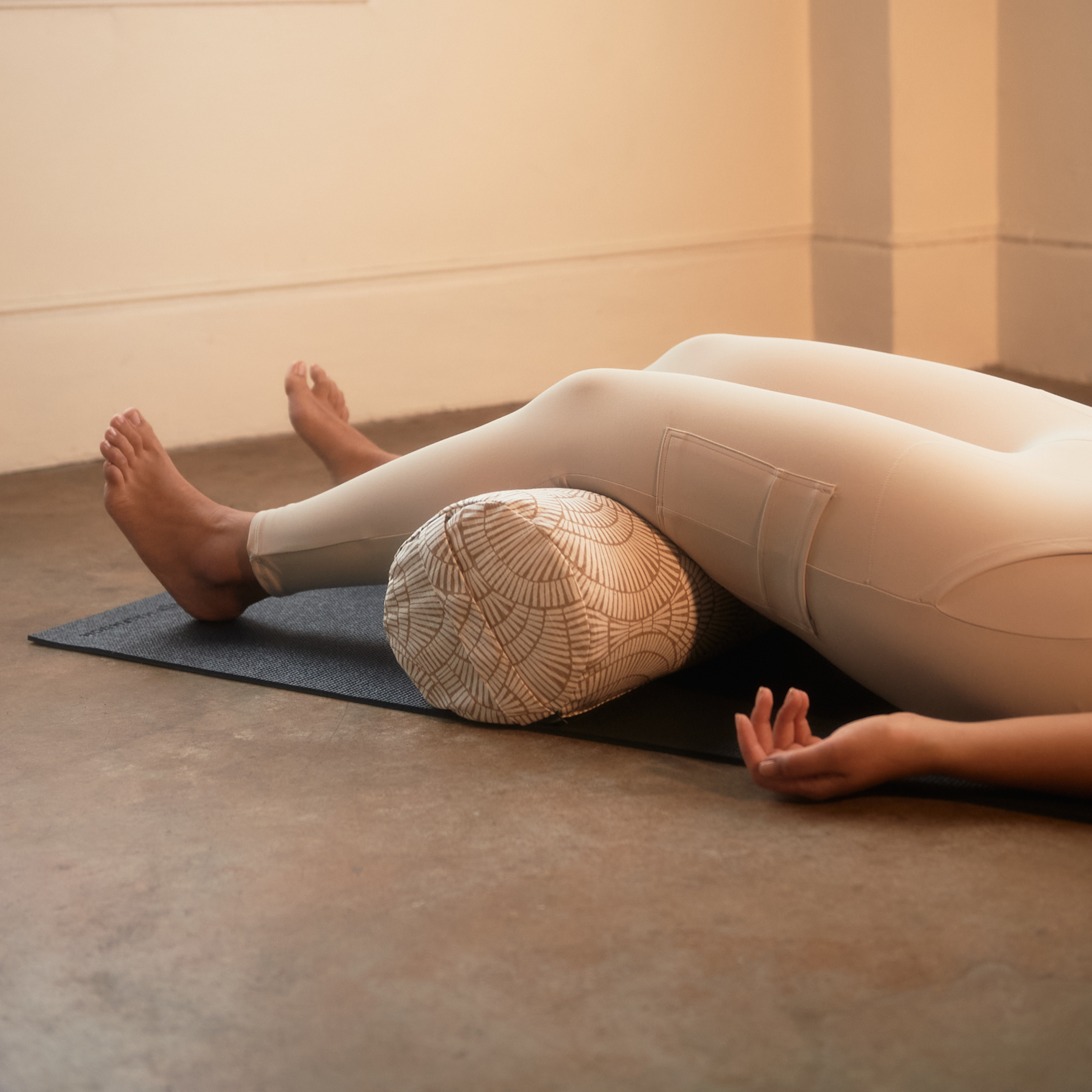 Person laying on floor with knees over bolster